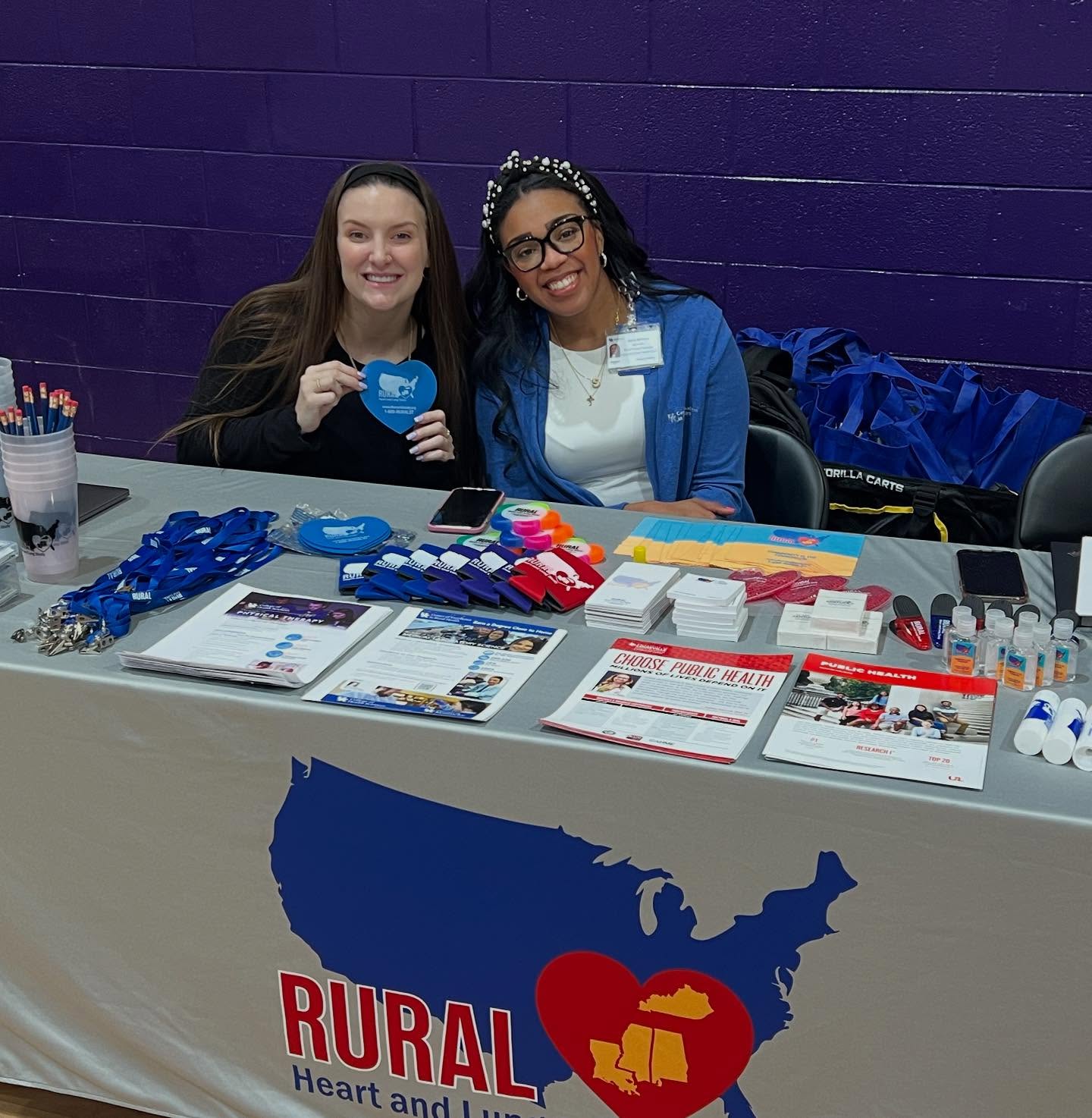 Career Fair (1) Scottland Stewart and Sierra Williams posed in front of a table with the RURAL logo and swag, at the College and Career Fair at Jackson Independent School
