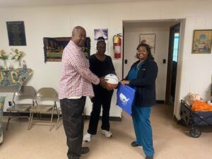 two women and a man holding a basketball and smiling