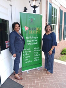 two woman smiling next to blackbelt hope sign