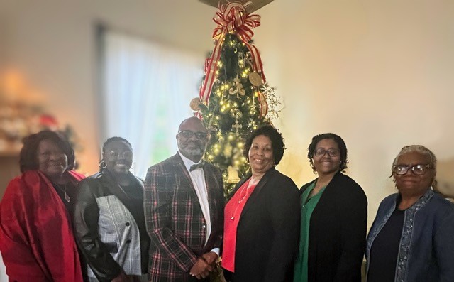 group of people smiling in front of christmas tree