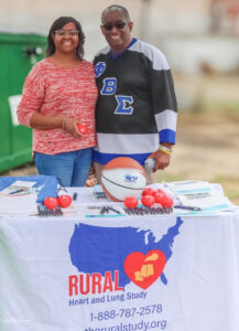 man and woman smiling in front of rural info table