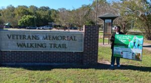 veterans memorial walking trail, woman holding sign