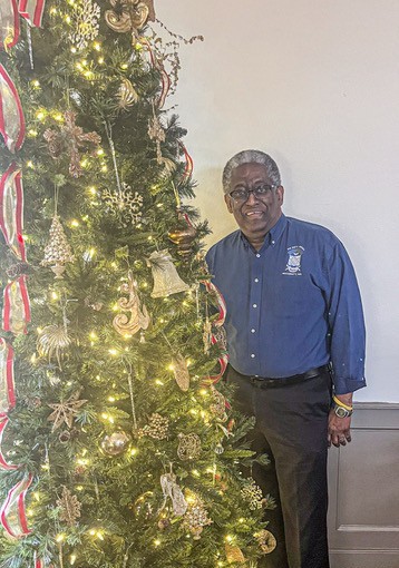 man standing next to christmas tree