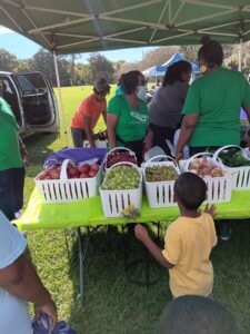 group of people around a table full of baskets of fruit