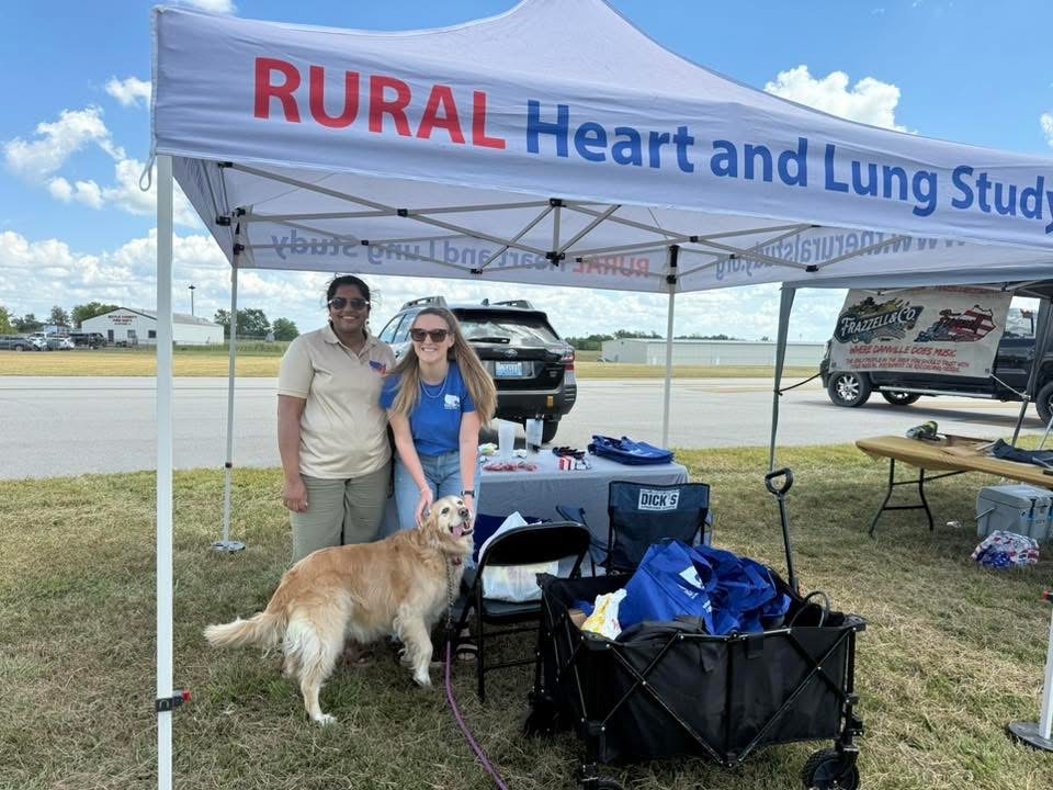 Two women and a dog under the RURAL tent